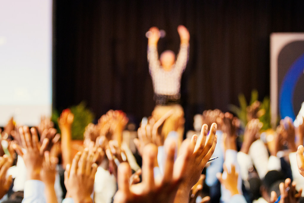 People raise hands to speaker at a conference event